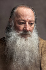 old man with a long beard with sadness on a Gray background