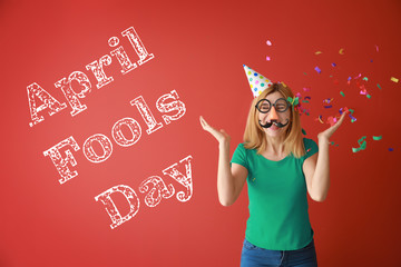 Funny woman with party decor and confetti for April Fools' Day on color background