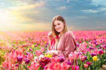 Obraz na płótnie Canvas Beautiful young woman in tulip field on spring day