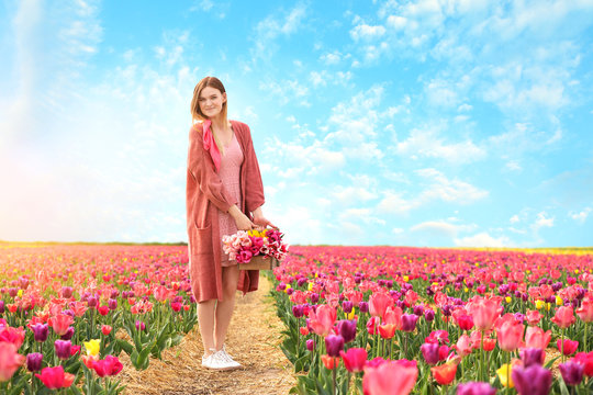 Beautiful young woman in tulip field on spring day