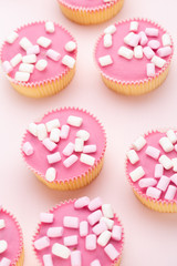 Colorful cupcakes on a pink background.