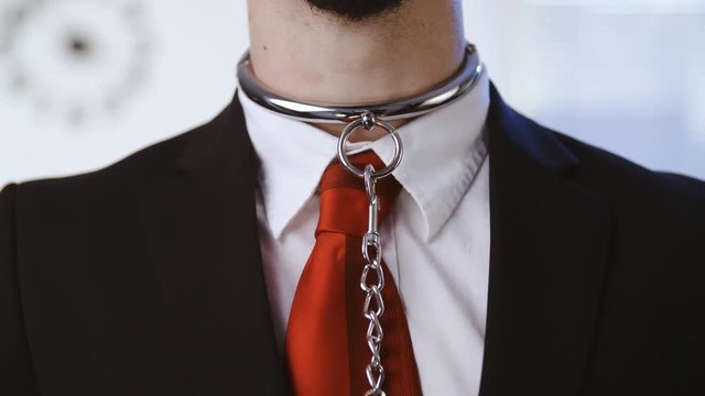 Enslaving a business person wearing bondage collar 4K. Closeup shot of a male person chest and neck in focus with a red tie.