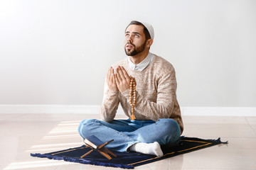 Young Muslim man praying indoors