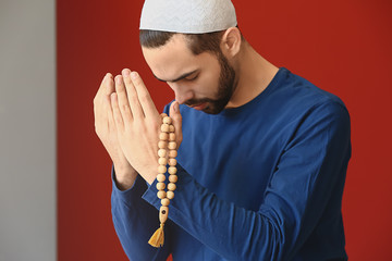 Young Muslim man praying indoors