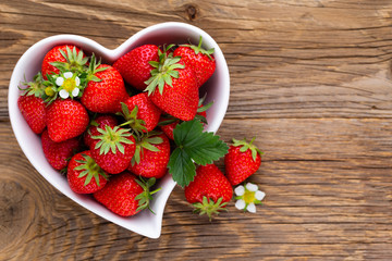 Strawberry heart. Fresh strawberries in plate on white wooden table. Top view, copy space.