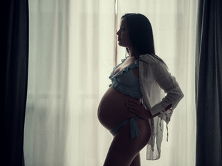 Pregnant woman standing against window