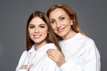 Portrait of happy mother with her daughter on grey background