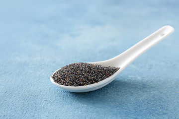 Spoon with poppy seeds on table