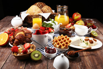 Huge healthy breakfast on table with coffee, orange juice, fruits, waffles and croissants. Good...