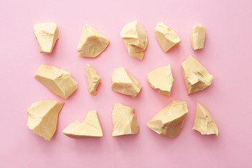 Pieces of cocoa butter on color background