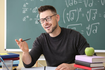 Handsome math teacher conducting lesson in classroom