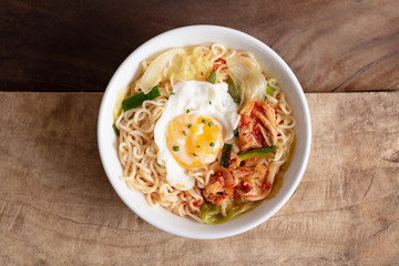 Kimchi noodle spicy soup with egg and vegetables on wooden background, Korean food