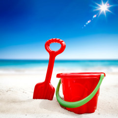 Red plastic bucket with free space for your product. The possibility of mounting bottles with drink, ice cream, food or other products. Blurry beach with people and ocean view.