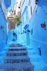 Papier Peint photo Bleu Belle architecture marocaine typique dans la médina de la ville bleue de Chefchaouen au Maroc avec des murs bleus, des détails, des pots de fleurs colorés et des articles ménagers