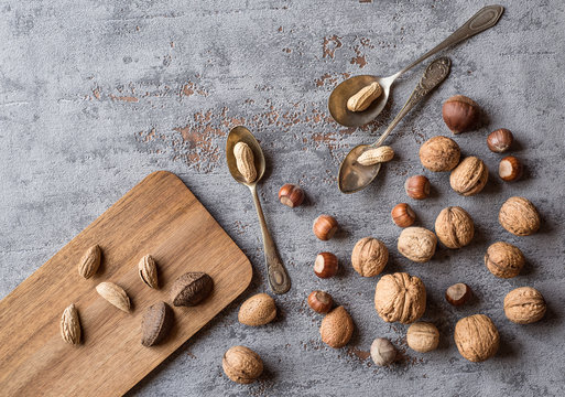 Nuts on a beautiful background and vintage spoons. Background to advertise nuts. Walnuts, peanuts, hazelnuts on a vintage plate
