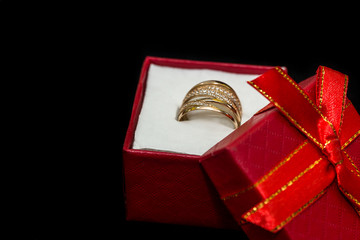 Golden ring in small red box is isolated on black background