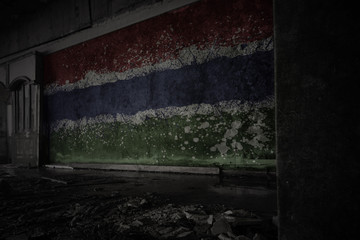painted flag of gambia on the dirty old wall in an abandoned ruined house.