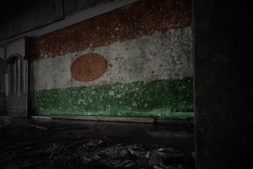 painted flag of niger on the dirty old wall in an abandoned ruined house.