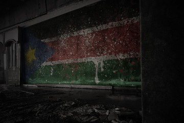 painted flag of south sudan on the dirty old wall in an abandoned ruined house.