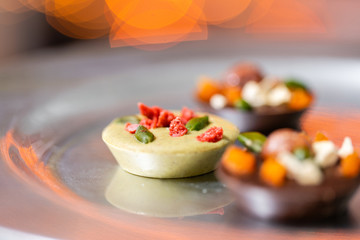 Christmas theme. Handmade chocolates candy. Mini chocolate dessert covered with nuts and dried fruits. Garland lamps bokeh on background. Copy space