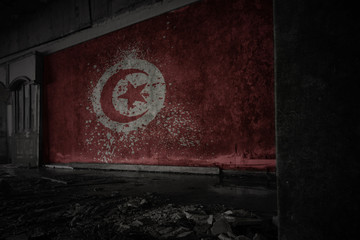 painted flag of tunisia on the dirty old wall in an abandoned ruined house.