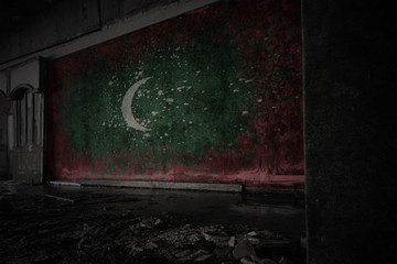 painted flag of maldives on the dirty old wall in an abandoned ruined house.