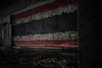 painted flag of thailand on the dirty old wall in an abandoned ruined house.