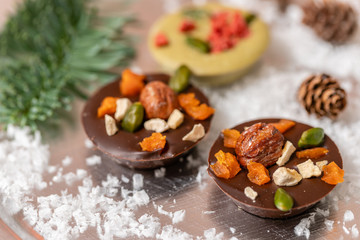 Christmas theme. Handmade chocolates candy. Mini chocolate dessert covered with nuts and dried fruits. Garland lamps bokeh on background. Copy space