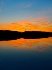 Obraz premium Bright colorful sunset over a lake. Beautiful reflection by a tranquil water of amazing sky and the lakeside at sundown in the summer evening. Lake Elovoe (Spruce Lake), South Ural, Russia.