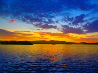 Fototapeta na wymiar Bright colorful sunset over a lake. Beautiful reflection by a tranquil water of amazing sky and the lakeside at sundown in the summer evening. Lake Elovoe (Spruce Lake), South Ural, Russia.