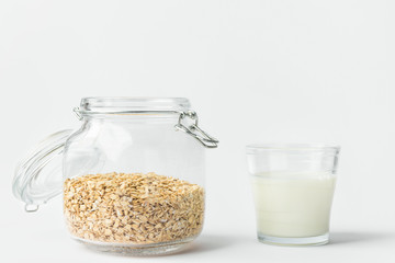 Glass of non-diary animal-free plant based milk rolled oats in reusable crystal on white kitchen table wall background. Healthy lifestyle vegan diet zero waste plastic free storage solutions concept