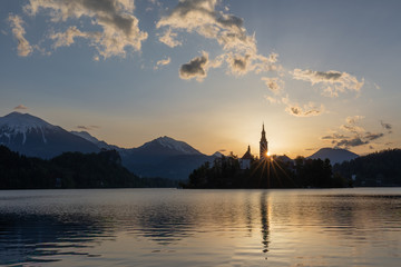 Fototapeta na wymiar First light of sunrise on tower of church at Lake Bled