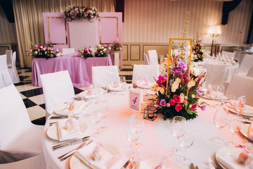 Round white table with elegant compositions from natural flowers. Banquet at the luxury wedding. Elegant design wedding table.