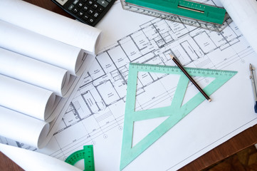 On the table are folded drawings of the apartment, working documentation, compass, ruler and pencil