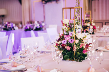 Fototapeta na wymiar Round white table with elegant compositions from natural flowers. Banquet at the luxury wedding. Elegant design wedding table.