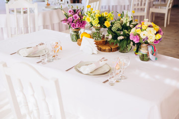 Round white table with elegant compositions from natural flowers. Banquet at the luxury wedding. Elegant design wedding table.