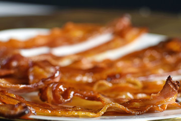 Baked bacon on white plate. Shallow depth of field.