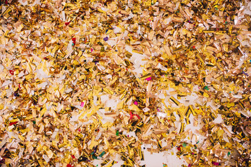 Golden Confetti on a wooden floor reflecting red stage spotlight causing colorful glow