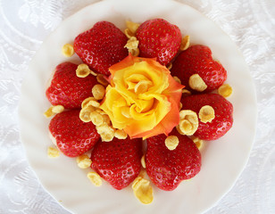 Beautiful cultivated deep red delicious strawberries, macro photography, decoration with fruit in white plate with peaces and beautiful rose flower