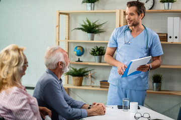 Happy doctor talking with a senior couple at his office.