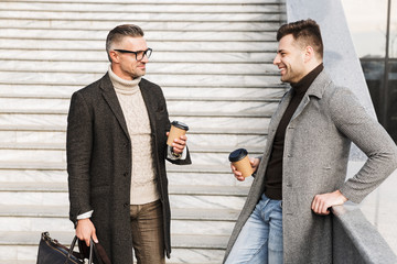 Two handsome men wearing coats spending time