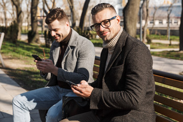 Two handsome men wearing coats spending time