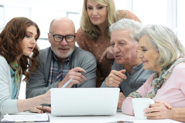 Two senior couples talking with consultant while sitting at table