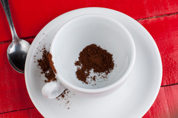 White coffee cup with metal spoon isolated on a red background.