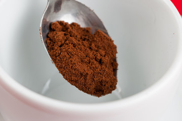 White coffee cup with metal spoon isolated on a red background.