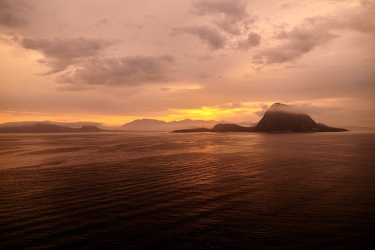 Rock in the ocean with clouds in sunrise