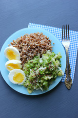 Buckwheat with vegetables. On a wooden background. The view from the top. Copy space. Healthy Breakfast with egg, salad and buckwheat porridge on a dark background. Proper diet. Diet menu.
