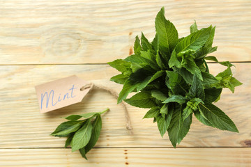 Mint. Leaves and branches of fresh green wild mint with a sign with the text on a wooden natural table. top view