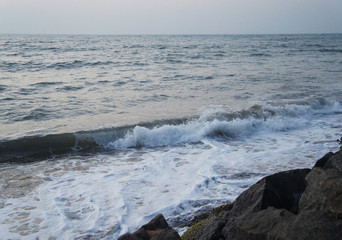 Southern tropical summer evening ocean coast at sunset. Restless sea and waves.