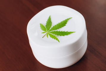 Detail of cannabis hemp cream with marijuana leaf - cannabis topicals concept. Cream from biological and ecological plants of hemp vegetable pharmaceutical oil CBD
